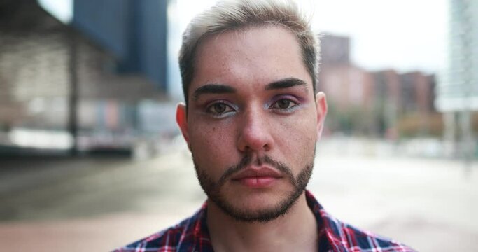 Young transgender man with makeup looking on camera outdoor