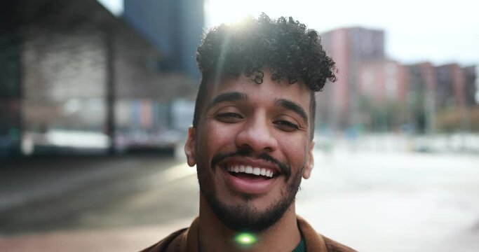 Young latin man smiling on camera in the city