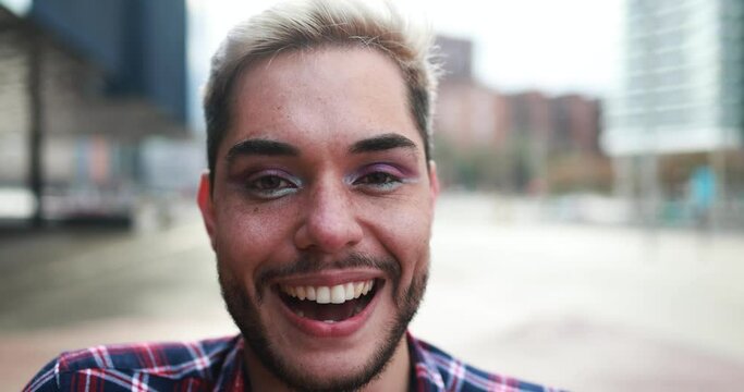Young transgender man with makeup smiling on camera outdoor