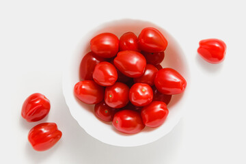 Cherry tomatoes in bowl on white background.