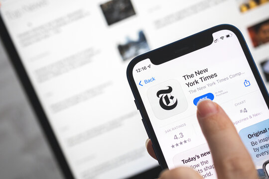 The New York Times app icon. Woman use news application, breaking news concept photo
