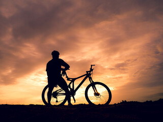 Fototapeta na wymiar Silhouette of a male tourist and his bike, happiness and freedom. in the evening the light is beautiful