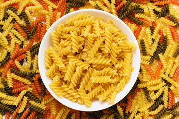 Raw pasta torti texture and fusilli in bowl.