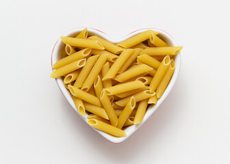 Raw pasta penne rigate in heart bowl.