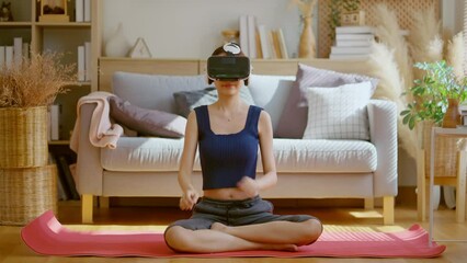 Peaceful clam asian female woman wearing virtual reality glasses meditating at home in breath train hands in namaste enjoying simulation and relax. Virtual technology experience in metaverse world - Powered by Adobe