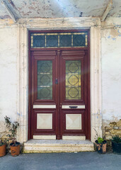 Fototapeta na wymiar Old Burgund wooden door with glasses. Details Classic vintage door and potted plants near the wall