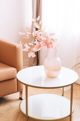 Obraz na płótnie Canvas Soft home decor, glass jug, vase with white and pink beautiful flowers against window and curtains and table top. interior. 