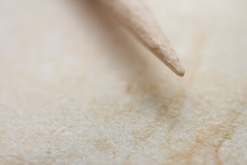 Extreme closeup of biege handmade paper with a toothpick