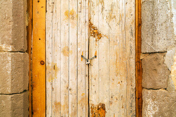 Rusty padlock locking old wooden door with a chain