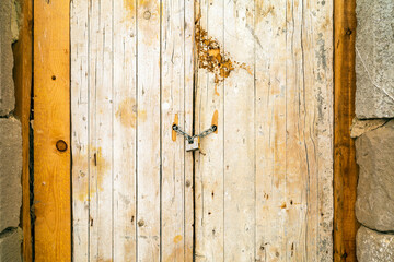Rusty padlock locking old wooden door with a chain