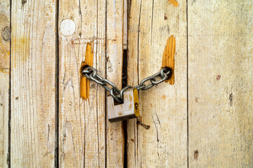 Rusty padlock locking old wooden door with a chain