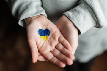 Heart of yellow-blue colors of national flag of Ukraine in childs hand. Top view. Stop War.