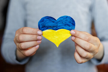 Heart of yellow-blue colors of national flag of Ukraine in childs hand. Top view. Stop War.