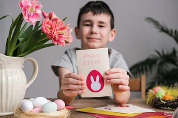 Happy boy making Easter greeting card. Materials for art creativity on kid table, children painting. Paper crafts activity in kindergarten or learning at home