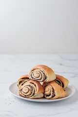 Homemade poppy seed roll buns on a white table