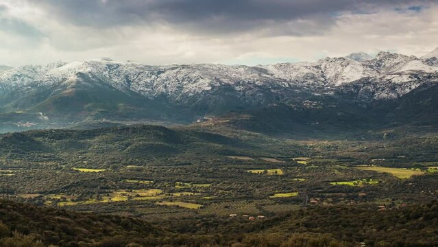 Panning time-lapse of the Regino valley in the Balagne region of Corsica with the snow capped mountains of Monte Padru, Monte San Parteo and Monte Grosso in the distance
