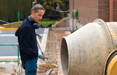 Young man learning how to make cement throwing gravel with a shovel