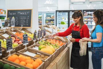 Female customer buying organic food fruits inside eco fresh market - Shopping concept - Focus on employee hand