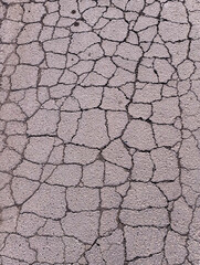 Old road background - surface of gray cracked asphalt close up