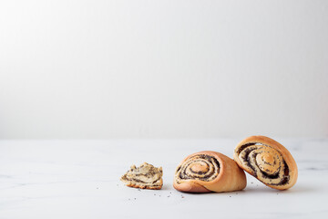 Homemade poppy seed roll buns on a white table