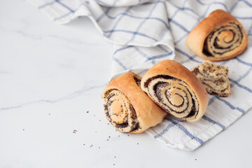 Homemade poppy seed roll buns on a white table