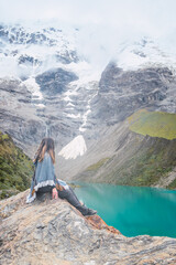 Side view of a caucasian woman sitting on a rock and wearing the typical peruvian poncho.