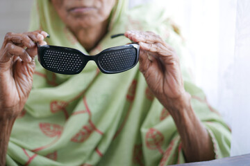 senior women holding perforation glasses with holes for training vision