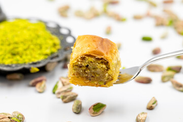 Baklava with pistachio on fork on a white background. Traditional Turkish cuisine delicacies. Close-up Pistachio Baklava. Local name fistikli baklava