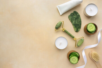 Jade roller and gua sha scraper for facial massage on beige background