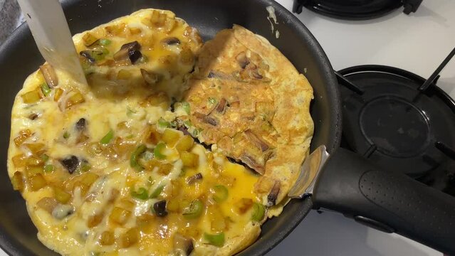 Preparing scrambled egg with potato pepper and mushroom at home for sunday breakfast  