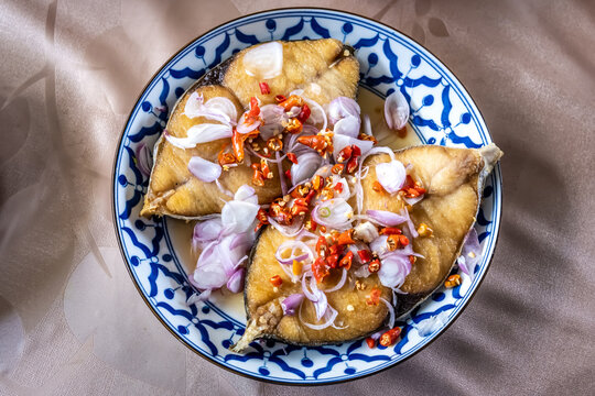 King mackerel or spotted mackerel steak on the plate. Fried Scomberomorus fish with sliced shallots and chili peppers