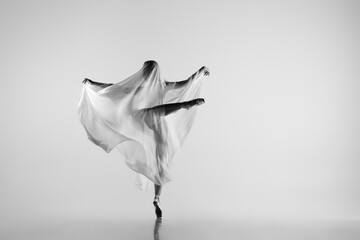 Black and white portrait of graceful ballerina dancing with fabric, cloth isolated on grey studio...