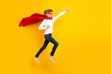 Fototapeta na wymiar Full size profile side photo of carefree playful male in superman costume childish behavior isolated on yellow color background