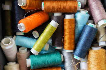 Background of many colorful spools of thread closeup. Sewing hobby concept. Pile of threads bobbins