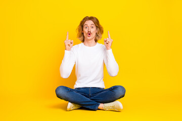 Photo of attractive impressed guy wear white shirt pointing fingers up empty space isolated yellow color background