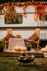 kindled a fire in front of the trailer. Camping autumn. Trailer on the background of the forest