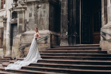 Charming bride stands on the stairs near the old church