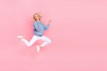 Fototapeta premium Full size photo of young cheerful lady promoter jump indicate fingers empty space promo select isolated over pink color background