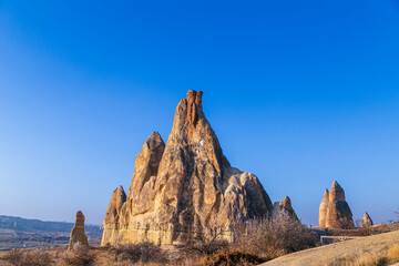 Fairy tale chimneys in Cappadocia with blue sky on background in Goreme,Nevsehir, Turkey. Volcanic rock landscape, Stone houses. 