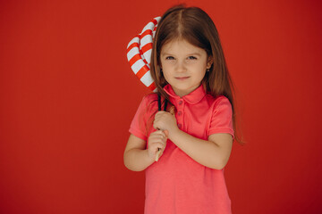 Little girl holding big lolly-pop isolated on red background