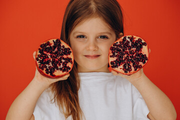 Little girl holding two halfs of garnet fruit