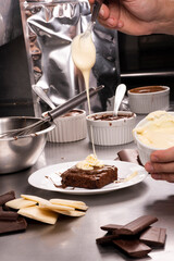 professionally producing sweets by pouring melted white chocolate into brownie in industrial kitchen