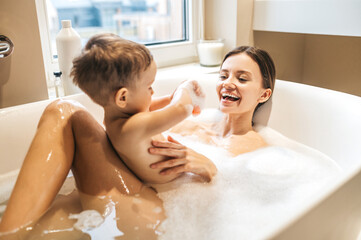 Obraz premium Joyful parent enjoying bathing with her baby
