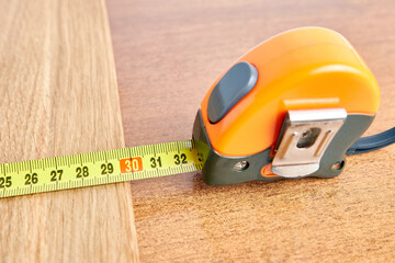 The length of a wooden board is measured with a tape measure.