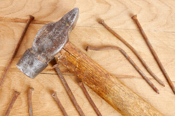 Old hammer and rusty curved nails. The concept of minor home repairs with their own hands.