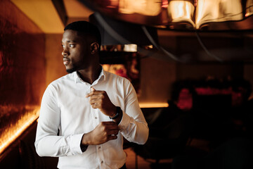 Portrait of handsome African American groom. Attractive charming man look at the camera, smiling, excited about marriage. Young adult business male in stylish formal wear