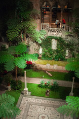 renaissance, byzantine and gothic style elements of arcade and a fountain decorating courtyard with tropical plants