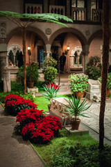 Fototapeta na wymiar renaissance, byzantine and gothic style elements of arcade and a fountain decorating courtyard with tropical plants