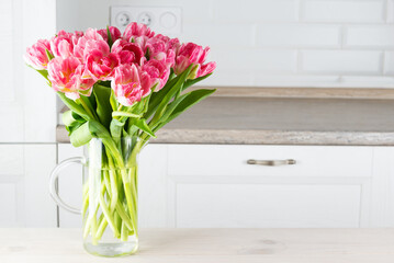 Bouquet of pink tulips in a vase on the kitchen table.