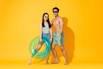 Summer portrait of smiling young Asian couple in studio isolated yellow color background